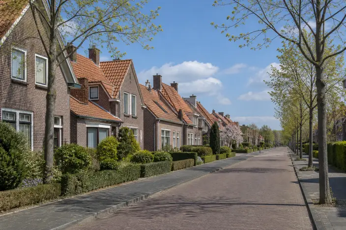 AI-beeld: een straat met bakstenen huizen en oranje pannendaken, op een zonnige lentedag